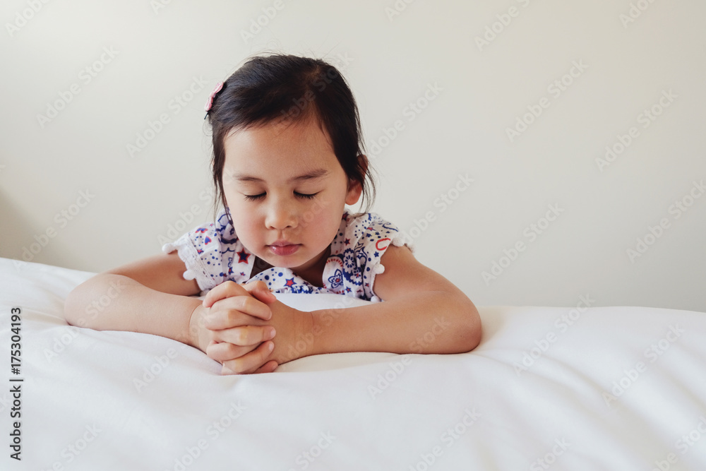 asian little girl praying on the bed asian little girl praying on the bed