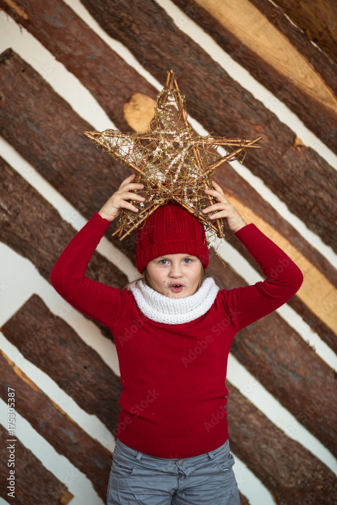 Fototapeta premium funny girl child in red hat with star, lifestyle, real interior, winter rustic style