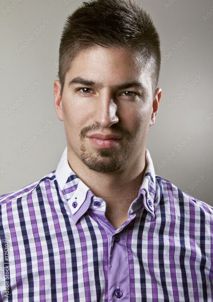 Fototapeta premium Portrait of young handsome man standing in front of camera, wearing nice shirt. 