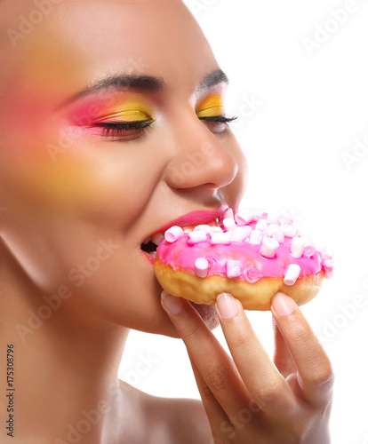 Attractive young woman eating delicious doughnut on white background