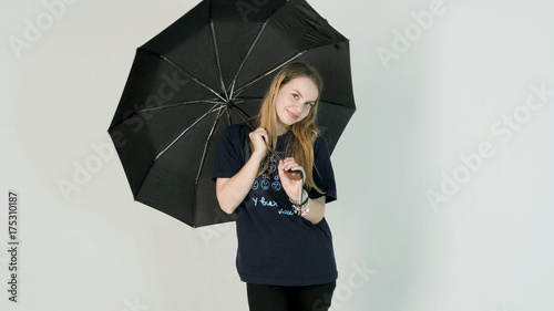 Young woman openes black umbrella on white background photo