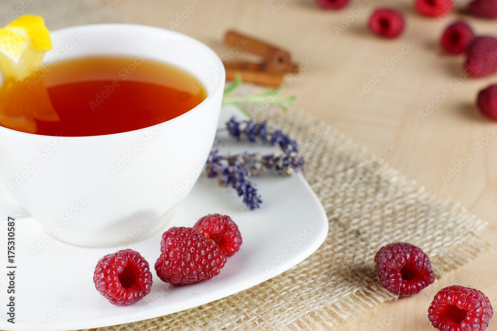 Mug of fruit tea and raspberries on cloth on the table Mug of fruit tea and raspberries on cloth on the table