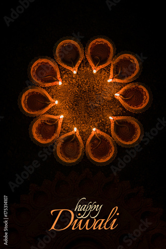 Happy Diwali greeting card design using Beautiful Clay diya lamps lit on diwali night Celebration.  Indian Hindu Light Festival called Diwali, a festival of light

