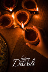 Happy Diwali greeting card design using Beautiful Clay diya lamps lit on diwali night Celebration.  Indian Hindu Light Festival called Diwali, a festival of light

