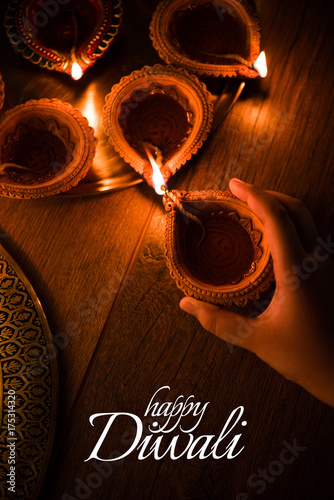 Happy Diwali greeting card design using Beautiful Clay diya lamps lit on diwali night Celebration.  Indian Hindu Light Festival called Diwali, a festival of light


