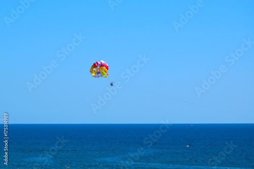 Tourists fly over the sea on a parachute behind a boat (Paraseyling).