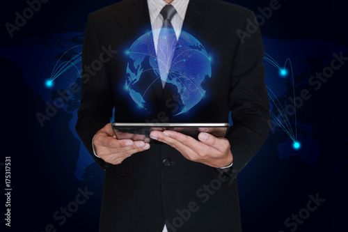 Businessman hand hold tablet and light blue polygon glowing technolgoy world map as business, technology, innovation and globalization concept.