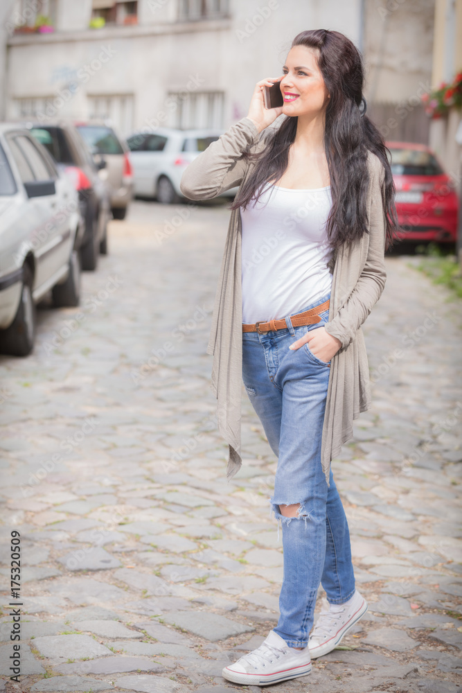 Cute girl using cellphone on the street.