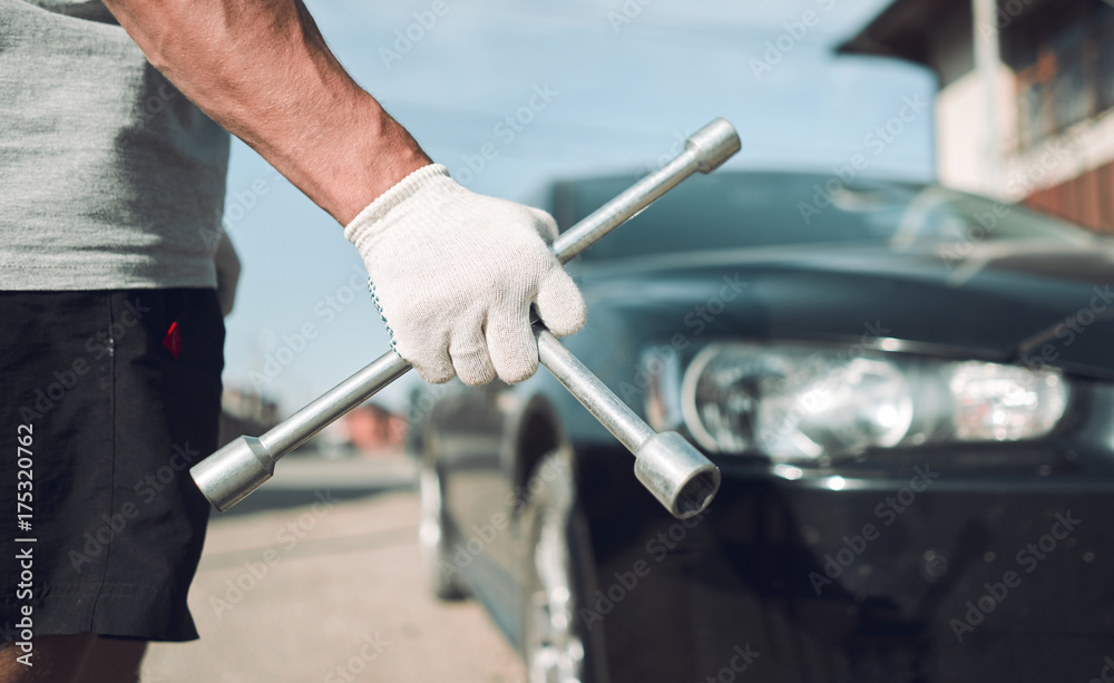 Close-up. The man is fixing the car. Cross-key for wheels. Wheel Replacement Close-up. The man is fixing the car. Cross-key for wheels. Wheel Replacement
