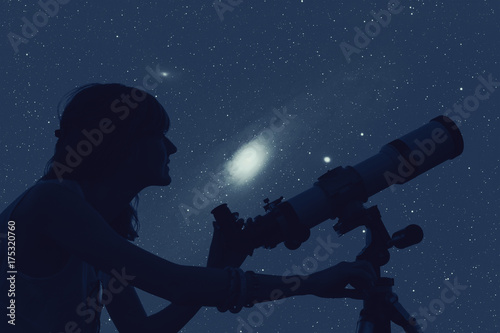 Silhouette of a girl while watching stars through the telescope.