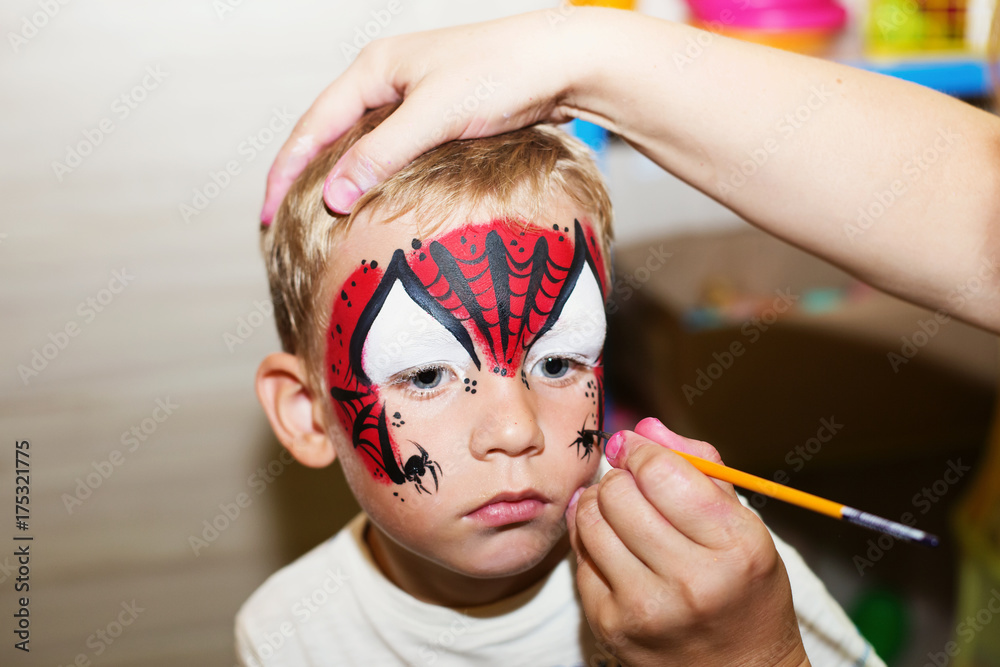 Obraz premium Mistrz robienia makijażu wodnego na twarzy chłopców