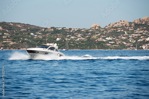 Small motor boat on sea, Sardinia island in background