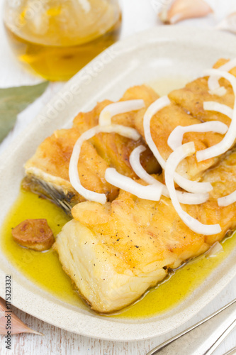fried cod fish with onion and olive oil on dish