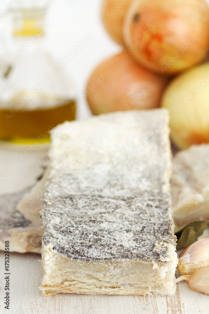 salted dry codfish with oil, garlic and onion on wooden background salted dry codfish with oil, garlic and onion on wooden background