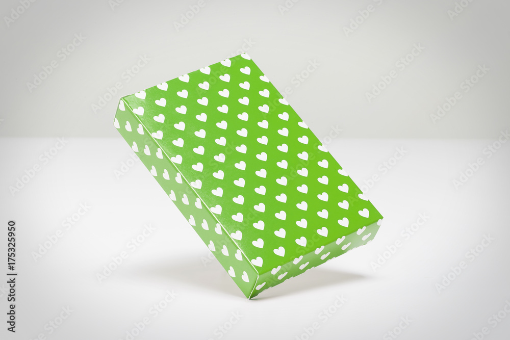Green gift box with hearts in white floating in a grey background Green gift box with hearts in white floating in a grey background