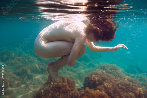 Beautiful woman is underwater swimming in blue sea