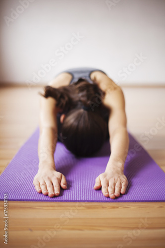 Beautiful and healthy woman in sportswear doing yoga in light room