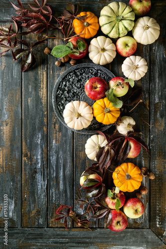 Autumn holiday table decoration setting with decorative pumpkins, apples, red leaves over wooden table. Rustic style, Flat lay, copy space