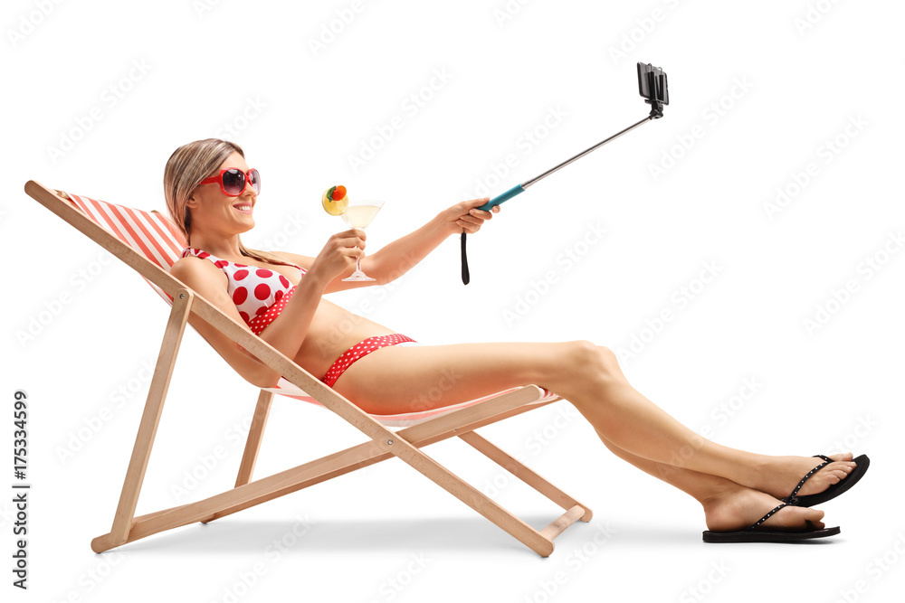 Young woman sitting in a deck chair and taking a selfie Young woman sitting in a deck chair and taking a selfie