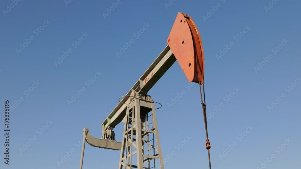 Operating oil and gas well in oil field, profiled against the blue sky. Operating oil and gas well in oil field, profiled against the blue sky.