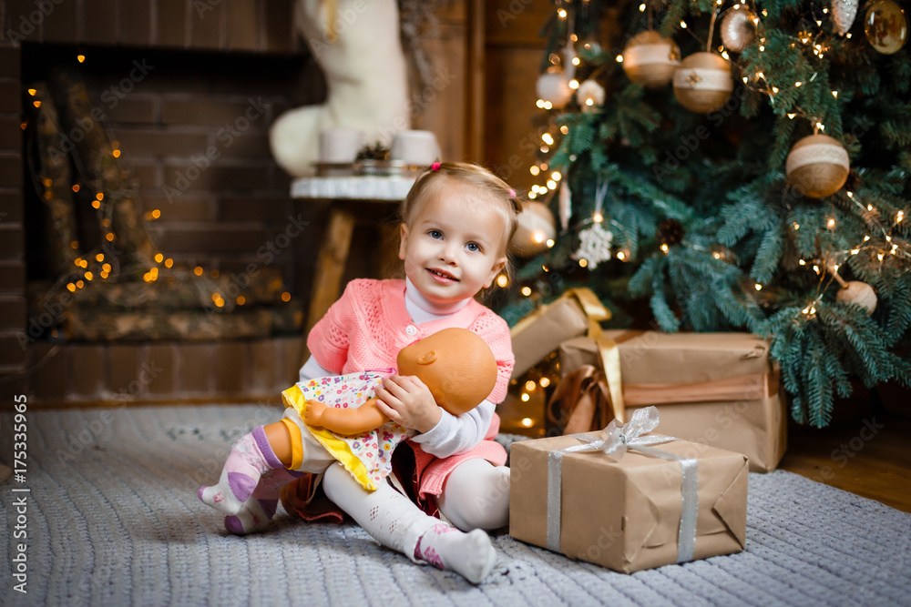 child little girl with gift box near christmas tree and fireplace at home child little girl with gift box near christmas tree and fireplace at home