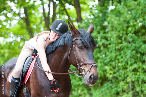 Young teenage girl-equestrian embracing her favorite frend-chestnut horse.