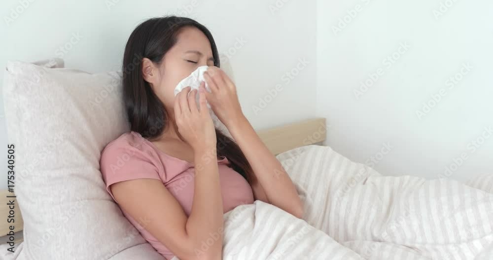 Woman getting sick and sneezing on bed Woman getting sick and sneezing on bed