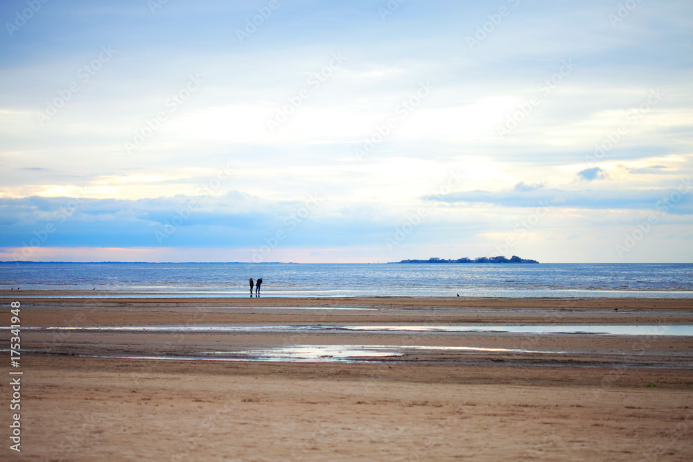 Two people on the sandy beach in cloudy weather