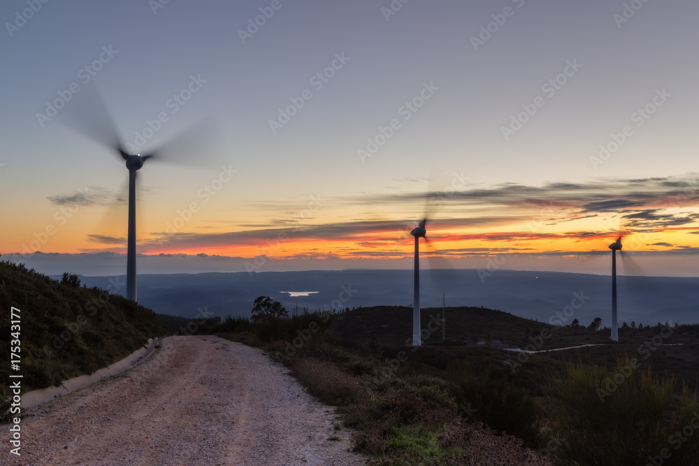 Obraz premium Magic sunset on the road with wind generators for electricity.