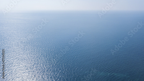 Vista aerea della superficie blu delle acque dell' oceano atlantico. Il sole, sopra l'orizzonte, riflette i suoi raggi solari sul mare.