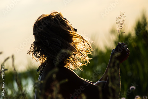 Silhouette of a beautiful girl in a field in sunset rays