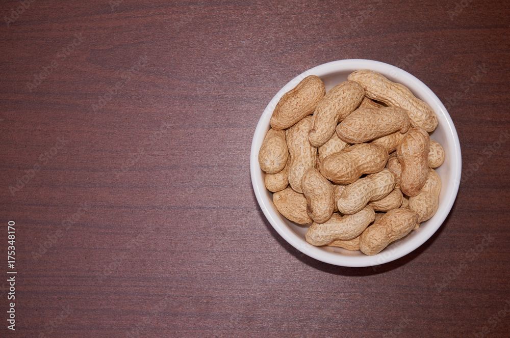 Peanuts uncleaned against a background of brown wood. Peanuts uncleaned against a background of brown wood.