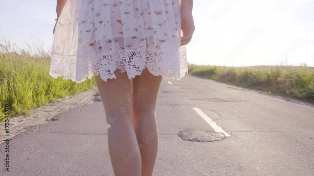 Young beautiful woman is skating on the skateboard at sunset on the country road Young beautiful woman is skating on the skateboard at sunset on the country road