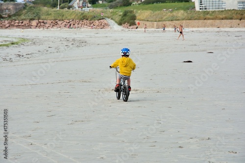 Un petit garçon qui fait du vélo sur une plage en Bretagne