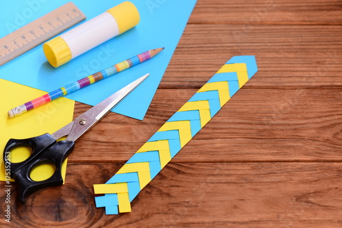 Kids paper bookmark on a brown wooden background with empty place for text. Paper craft for children with folding paper. Stationery set on a wooden table. Top view