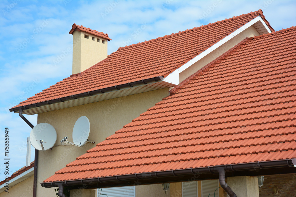 Modern house with chimney, red clay tiled roof and gable and valley type of roof construction. Building attic house construction with different types of roof designs.Roofing Construction.