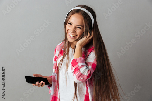 Close-up portrait of young laughing pretty woman in headphones listening to music