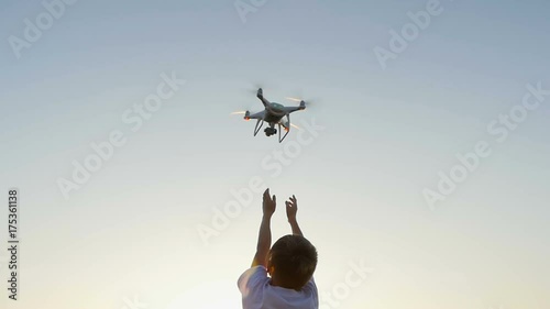 drone flies from the hands of the boy at sunset photo