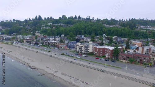 Early mourning Alki beach in Seattle, aerial shot of a car driving along a beach-side street at sunrise, establishing shot