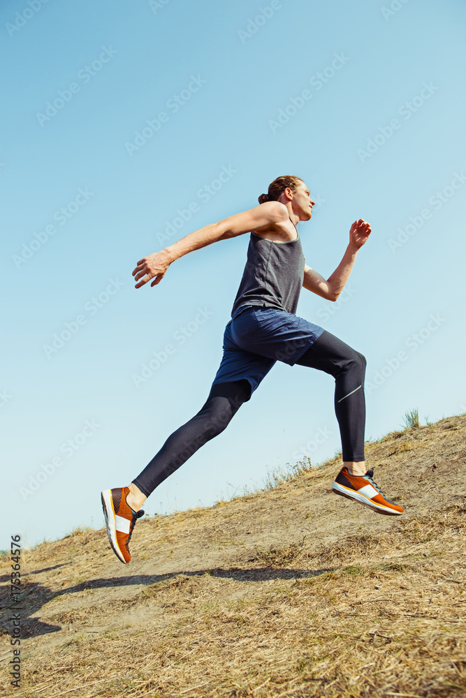 Running sport. Man runner sprinting outdoor in scenic nature. Fit muscular male athlete training trail running for marathon run. Running sport. Man runner sprinting outdoor in scenic nature. Fit muscular male athlete training trail running for marathon run.