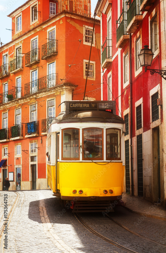 yellow tram on narrow street of Alfama, Lisbon, Portugal, retro toned