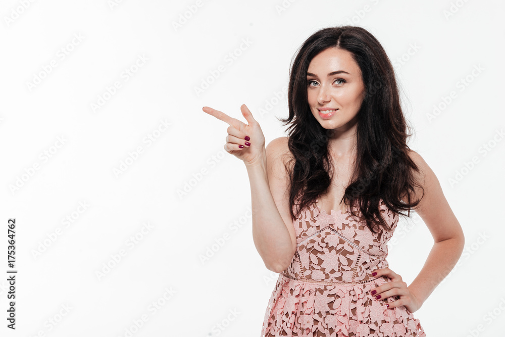 Portrait of a brunette woman in dress pointing finger away Portrait of a brunette woman in dress pointing finger away