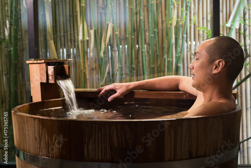 Onsen series: Asian man taking a bath in wooden bathtub