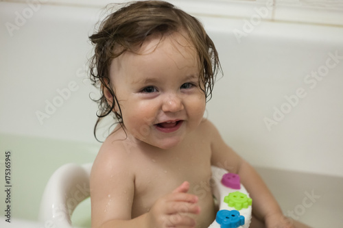 Photography Blue eyes little girl in the bathing bucket looking at the camera and smiling