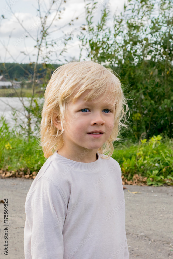 Portrait of a blond Slavic boy near river and the Urals village, Russia