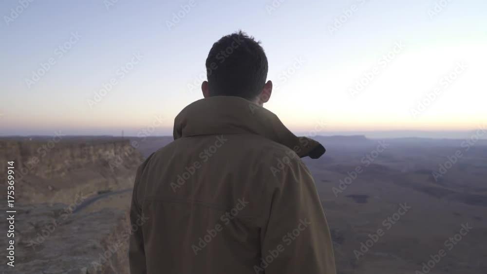 Man looking at the desert view from the edge of a cliff Man looking at the desert view from the edge of a cliff