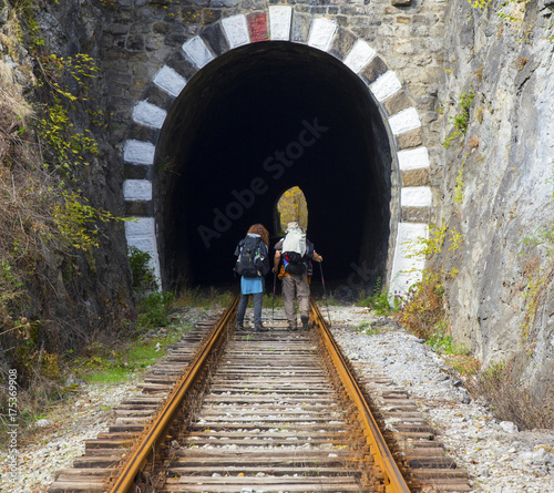 Family tourists with backpacks on railroad track