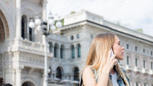 Pretty blonde teenager outdoor talking on her mobile phone. Photo taken in Milan, Italy. © tostphoto