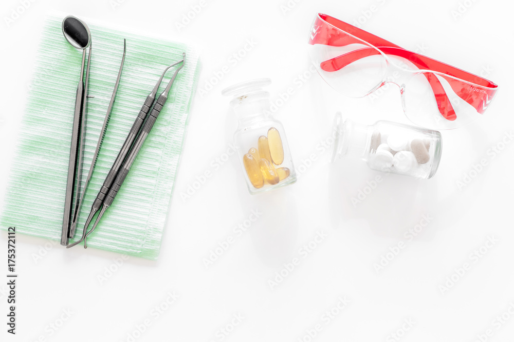 Dentists accessories. Tools, safety glasses and pills on white background top view copyspace