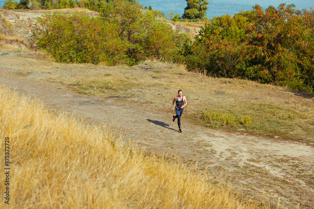 Running sport. Man runner sprinting outdoor in scenic nature. Fit muscular male athlete training trail running for marathon run.